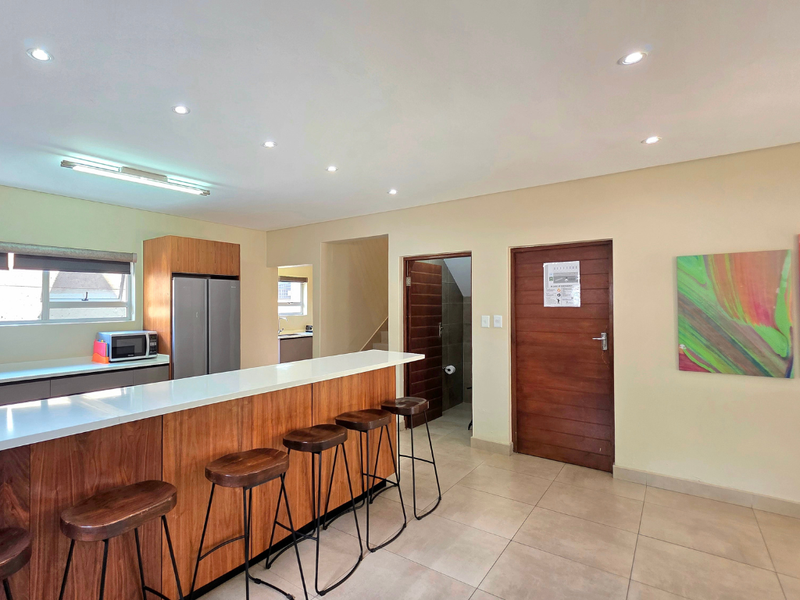 Open plan kitchen area featuring a breakfast bar with stone countertop, recessed lighting, and tiled flooring, leading to a separate doorway.