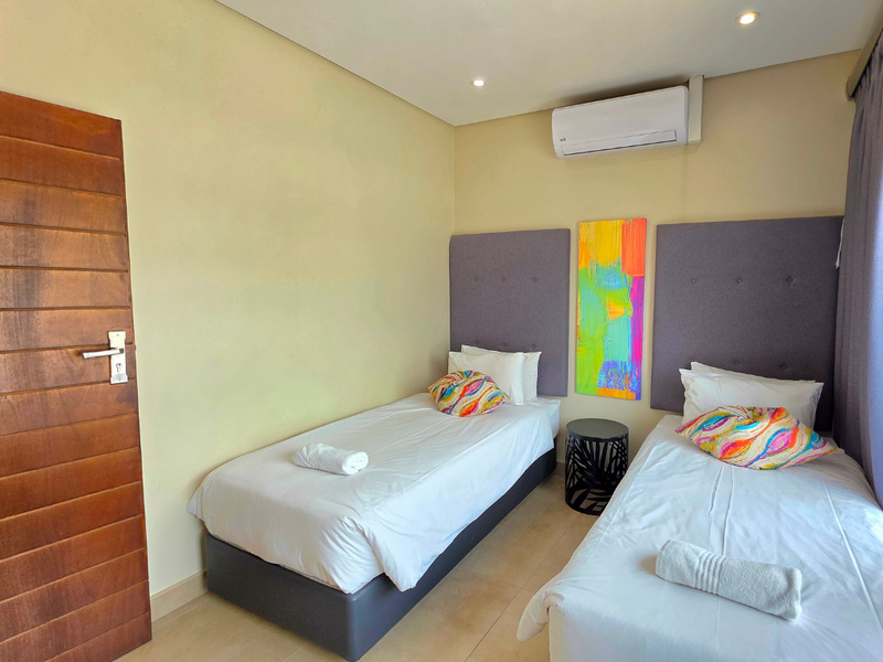A well-maintained bedroom featuring tiled flooring, a split-system air conditioner, and recessed downlighting, providing a comfortable and functional living space.