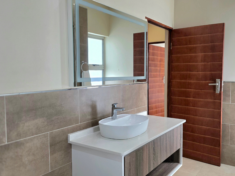 Modern bathroom featuring a contemporary vanity with a vessel sink, backlit mirror, and neutral wall tiling.