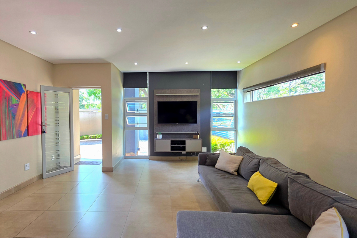 Modern living room featuring tiled floors, recessed lighting, and a built-in media unit with direct access to an outdoor area.