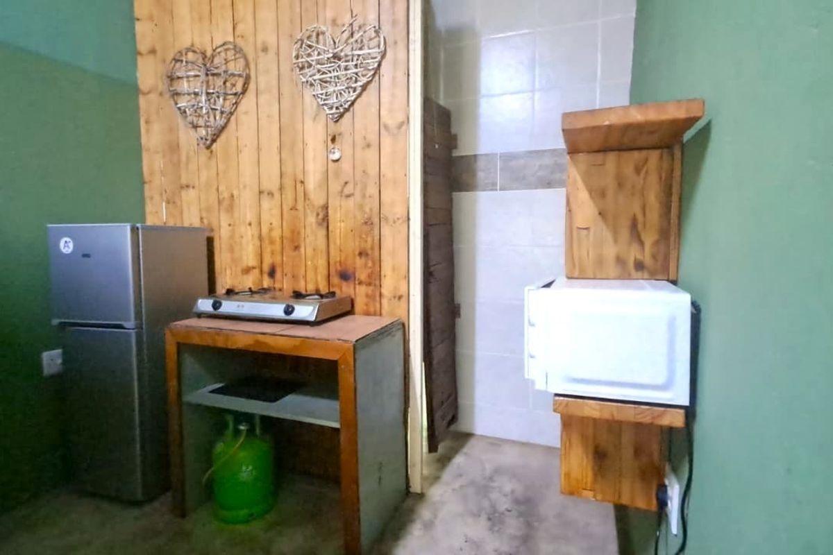 A compact kitchenette area featuring a gas hob, timber wall paneling, and tiled splashback, requiring modernization of finishes and fixtures.