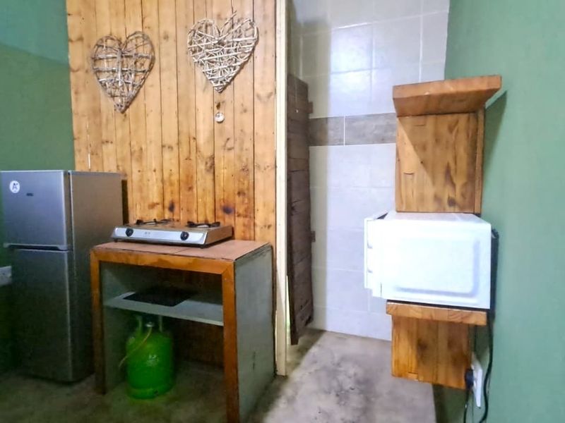 A compact kitchenette area featuring a gas hob, timber wall paneling, and tiled splashback, requiring modernization of finishes and fixtures.