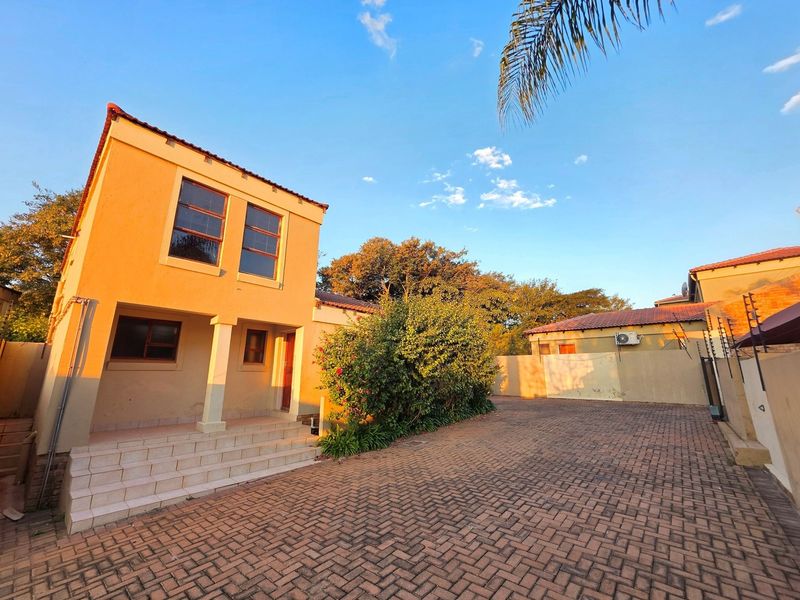 Exterior view of a two-story residential property featuring a paved driveway, tiled entrance steps, and secure perimeter walling with electric fencing.