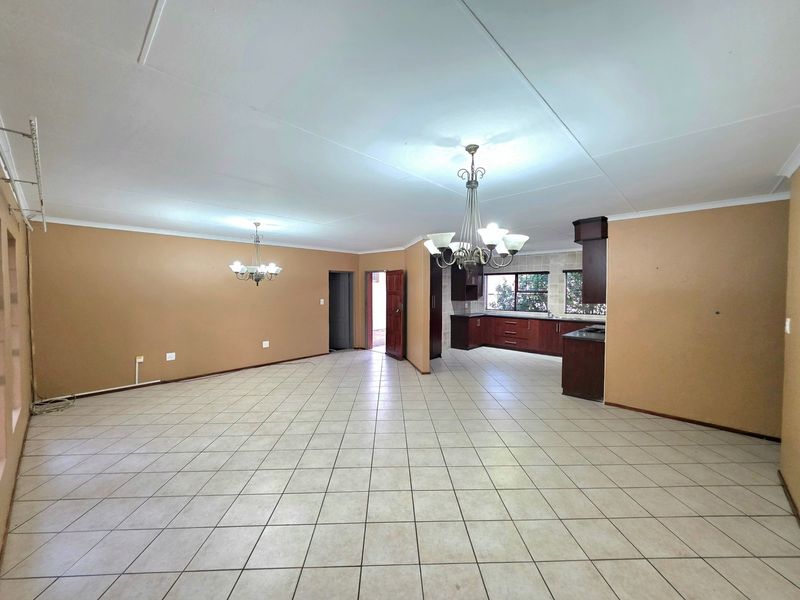 Spacious open-plan living and kitchen area featuring tiled flooring, built-in cabinetry, and classic chandeliers, offering a versatile layout for modern living.