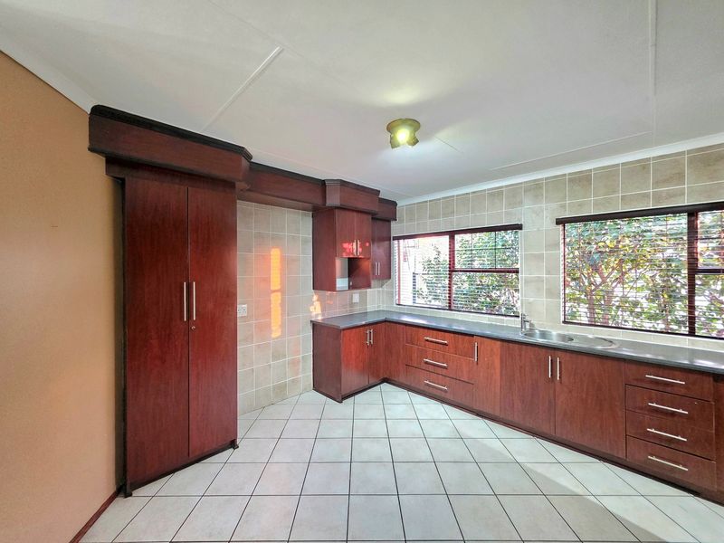 A functional kitchen featuring dark wood cabinetry, tiled backsplash, and tiled flooring, offering a clean and practical workspace.