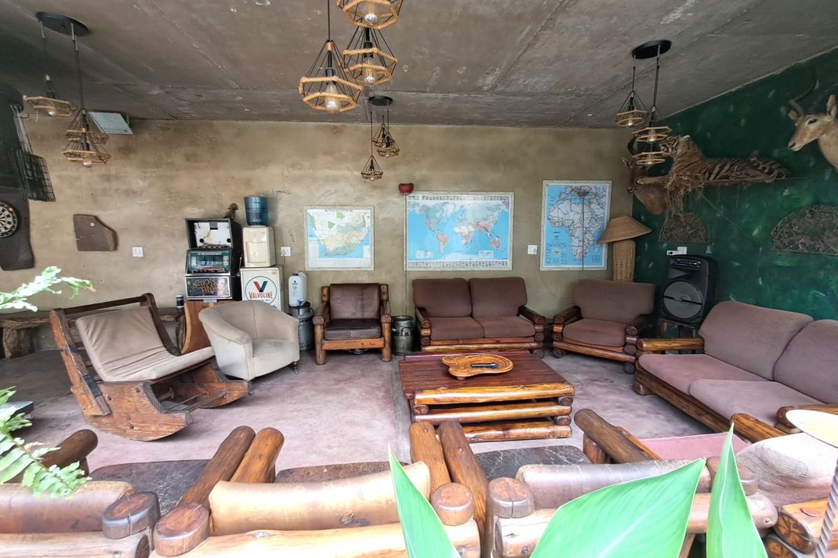 A rustic living area featuring an exposed concrete ceiling, pendant lighting, and raw wall finishes, offering a unique industrial-style space for potential renovation.