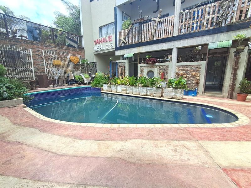 Outdoor pool area featuring a curved swimming pool with a tiled surround, set against a multi-level building facade with brick and concrete elements.