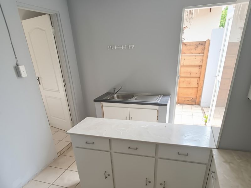 A compact kitchen area featuring built-in cabinetry, a stainless steel sink, and direct access to an outdoor space.