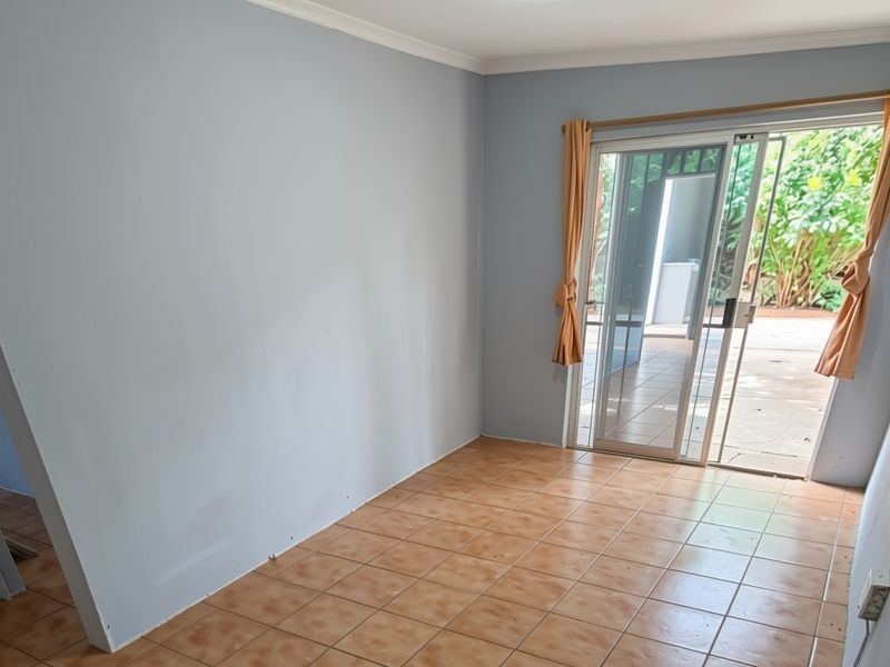 An empty living room featuring ceramic floor tiles and a sliding glass door providing direct access to an outdoor patio area.