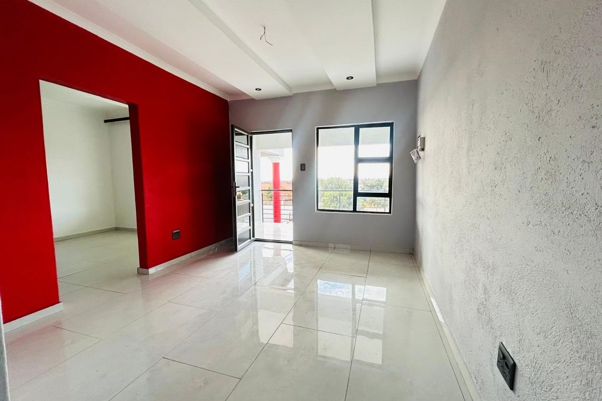 An empty, open-plan living area featuring polished porcelain floor tiles, a modern recessed ceiling, and direct access to a balcony through an aluminium door.