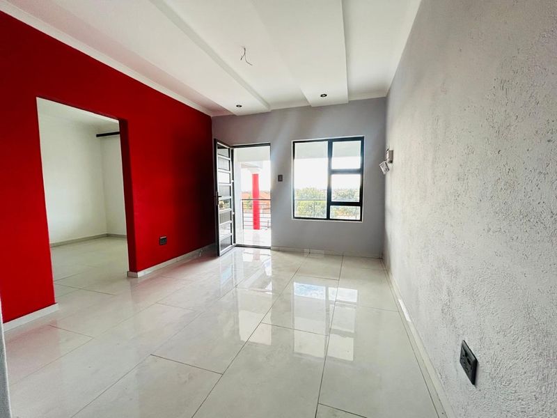An empty, open-plan living area featuring polished porcelain floor tiles, a modern recessed ceiling, and direct access to a balcony through an aluminium door.