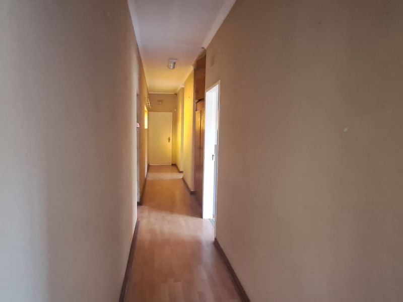 A functional hallway featuring laminate flooring and built-in storage cupboards, providing access to various rooms within the home.