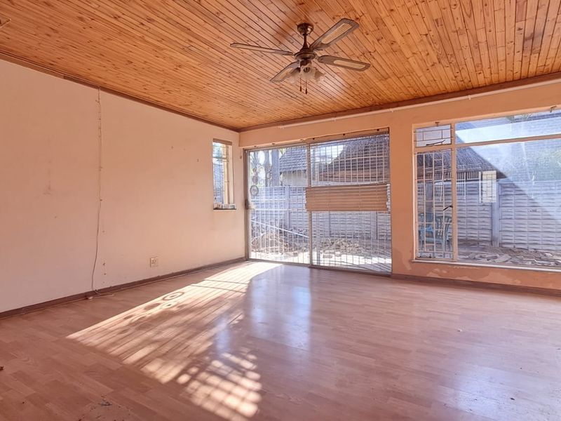 Spacious living area featuring a timber-clad ceiling, laminate flooring, and large windows with access to the rear exterior through a sliding glass door.