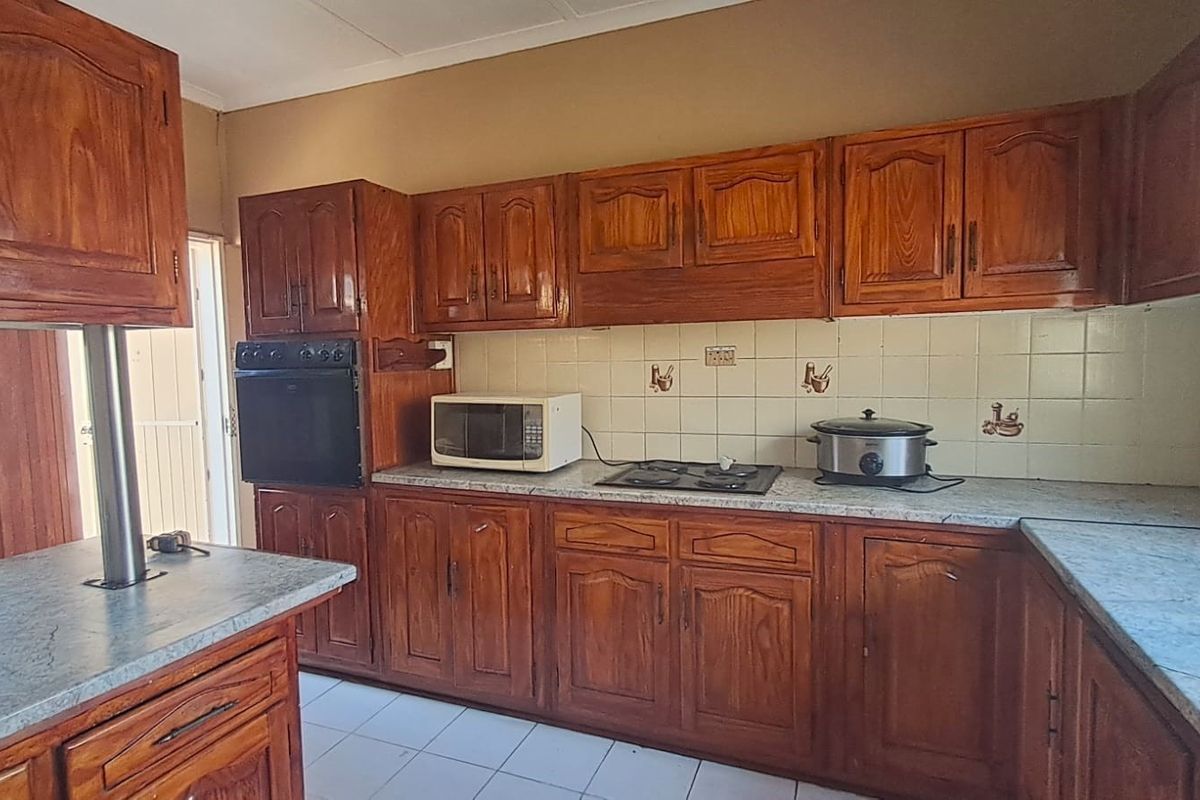 A functional kitchen featuring traditional wooden cabinetry, laminate countertops, a built-in oven, and a gas hob with a tiled backsplash.