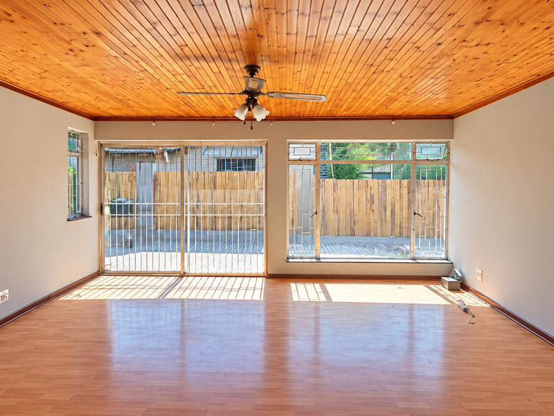 Spacious living area featuring a warm timber tongue and groove ceiling, laminate flooring, and large sliding doors providing access to the outdoor space.
