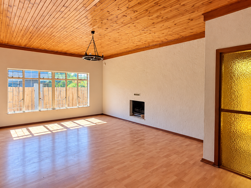 Spacious living room featuring a warm timber-clad ceiling, laminate flooring, and a built-in fireplace, offering a bright and versatile blank canvas.