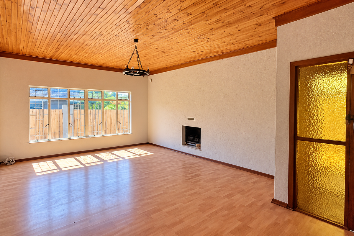 Spacious living room featuring a warm timber-clad ceiling, laminate flooring, and a built-in fireplace, offering a bright and versatile blank canvas.