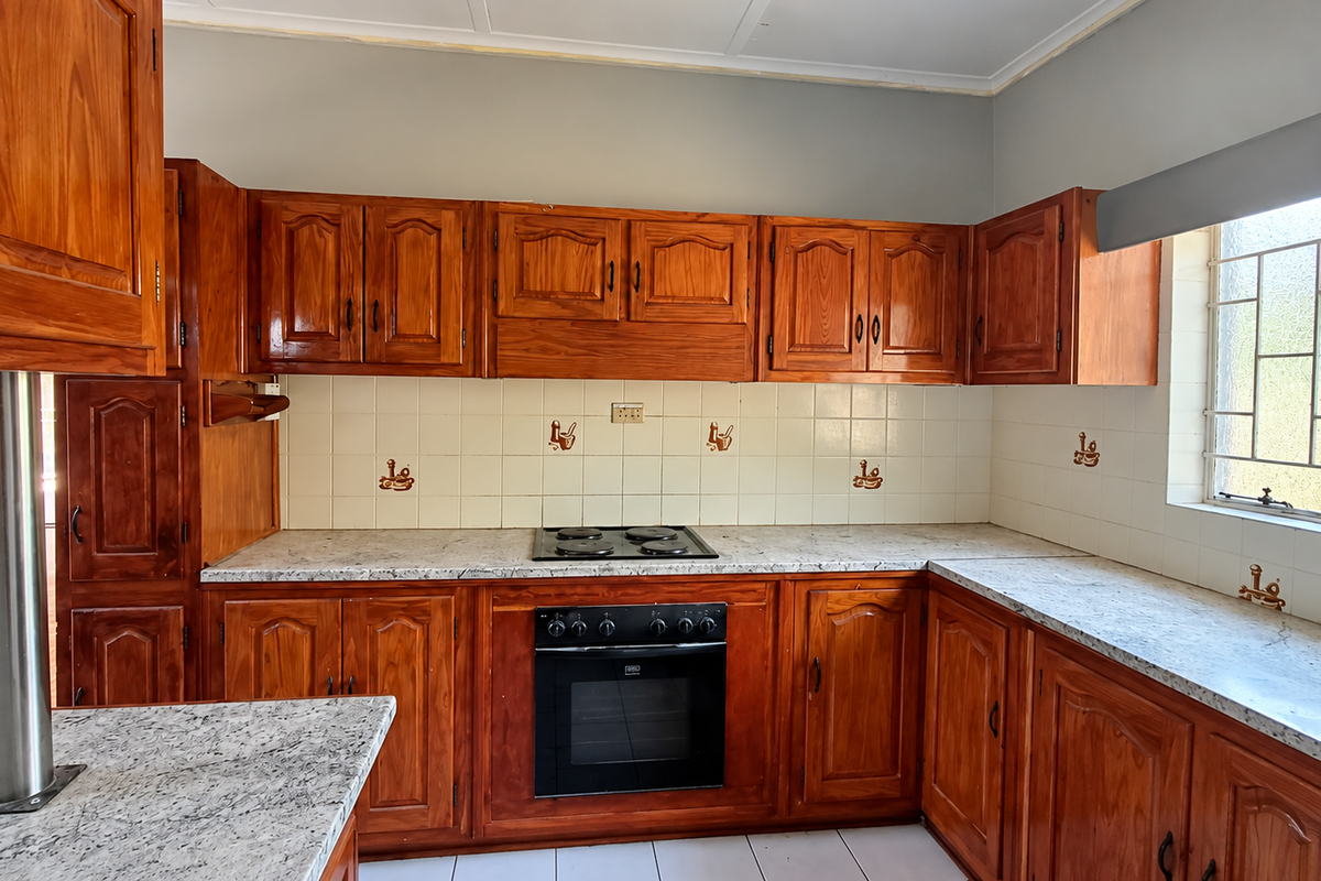 A functional kitchen featuring traditional wooden cabinetry, laminate countertops, a built-in oven, and an electric hob with a tiled backsplash.