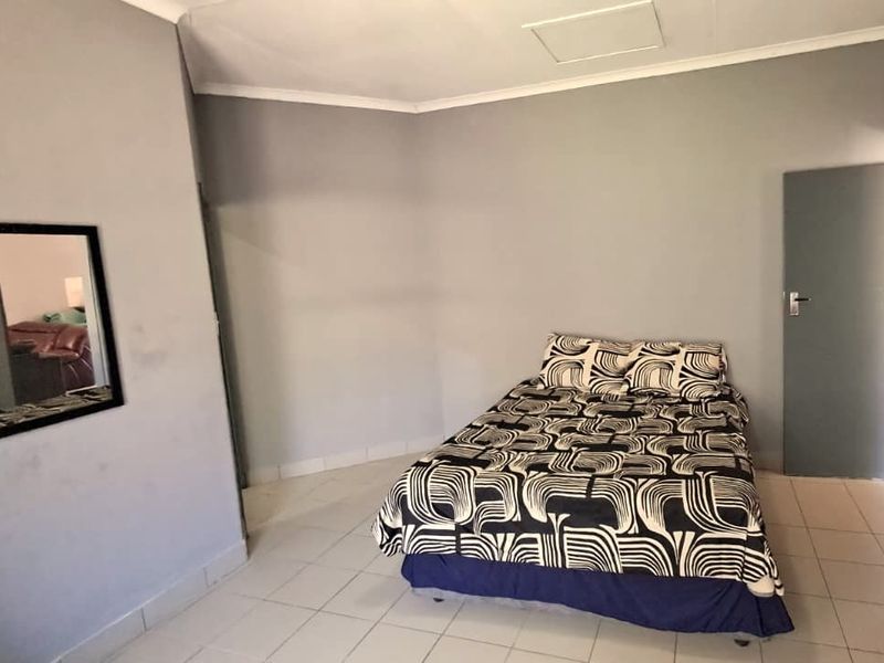A simple bedroom featuring tiled flooring and neutral grey walls, providing a functional space ready for personalization.