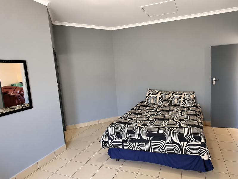 A bedroom featuring grey painted walls, tiled flooring, and decorative ceiling cornicing.