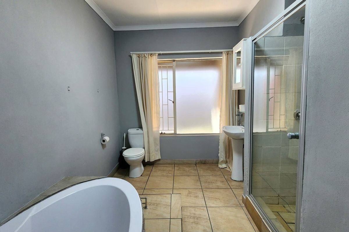 A functional bathroom featuring a freestanding bathtub, separate shower enclosure, pedestal basin, and toilet with tiled flooring.