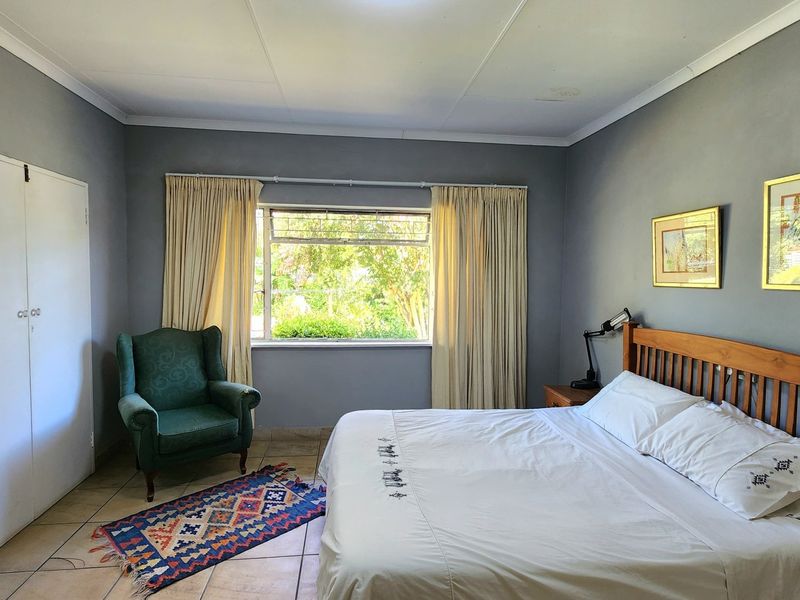 A spacious bedroom featuring tiled flooring, a large window with natural light, and a built-in wardrobe, offering a comfortable and functional living space.