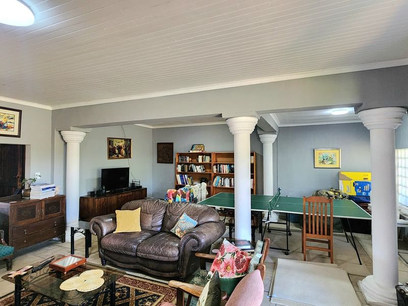 Spacious living area featuring decorative columns, tiled flooring, and a tongue and groove ceiling, offering a versatile layout for relaxation and recreation.