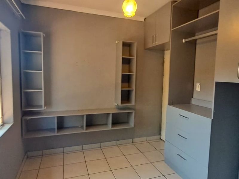 A bedroom featuring built-in cupboards, integrated shelving units, and tiled flooring, offering a functional space ready for personalization.
