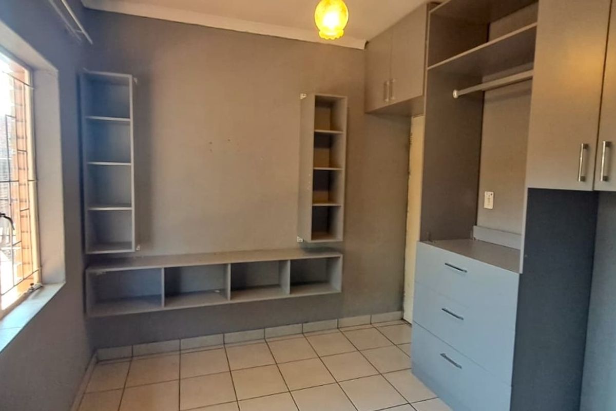 A bedroom featuring built-in cupboards, integrated shelving units, and tiled flooring, offering a functional space ready for personalization.
