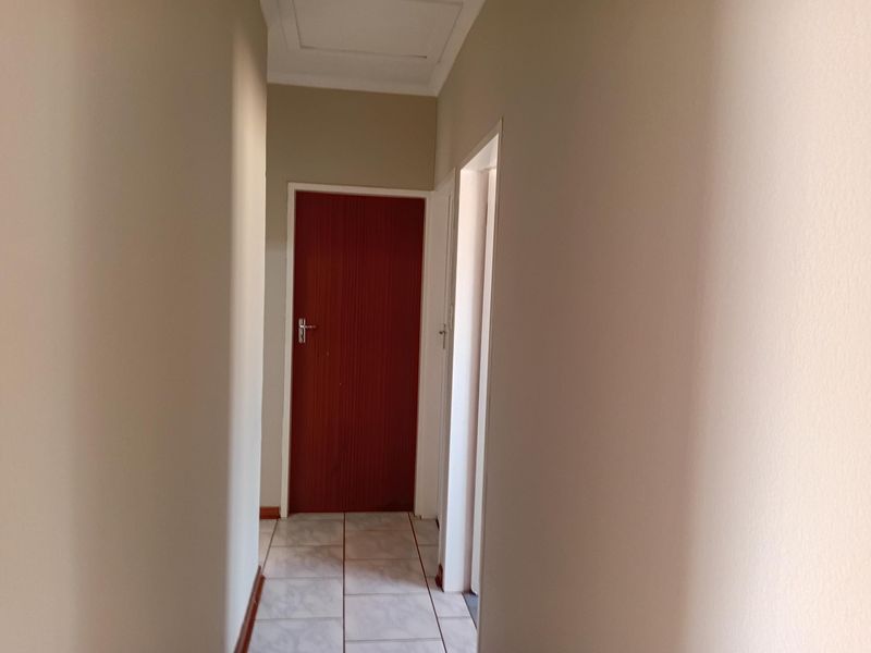 A clean, empty hallway featuring tiled flooring, neutral walls, and internal doors providing access to adjacent rooms.