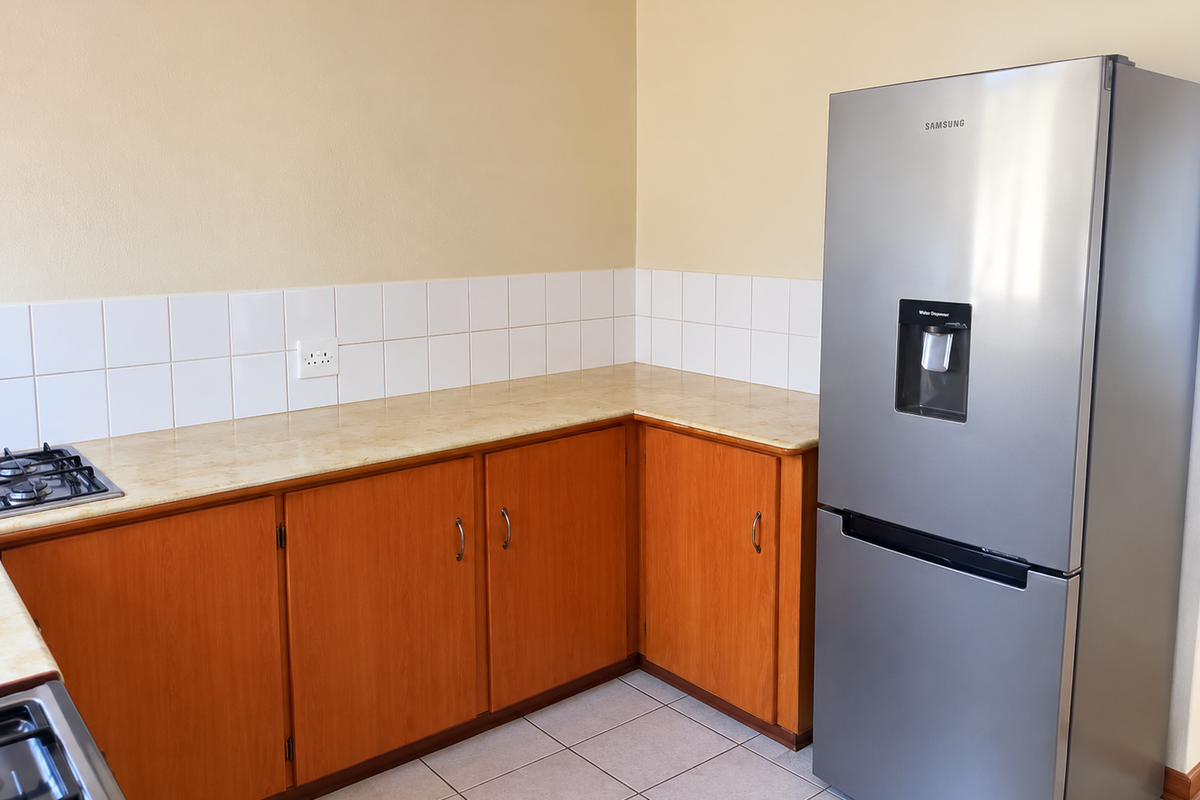 A functional kitchen area featuring wooden cabinetry, laminate countertops, tiled splashback, and a built-in gas hob.