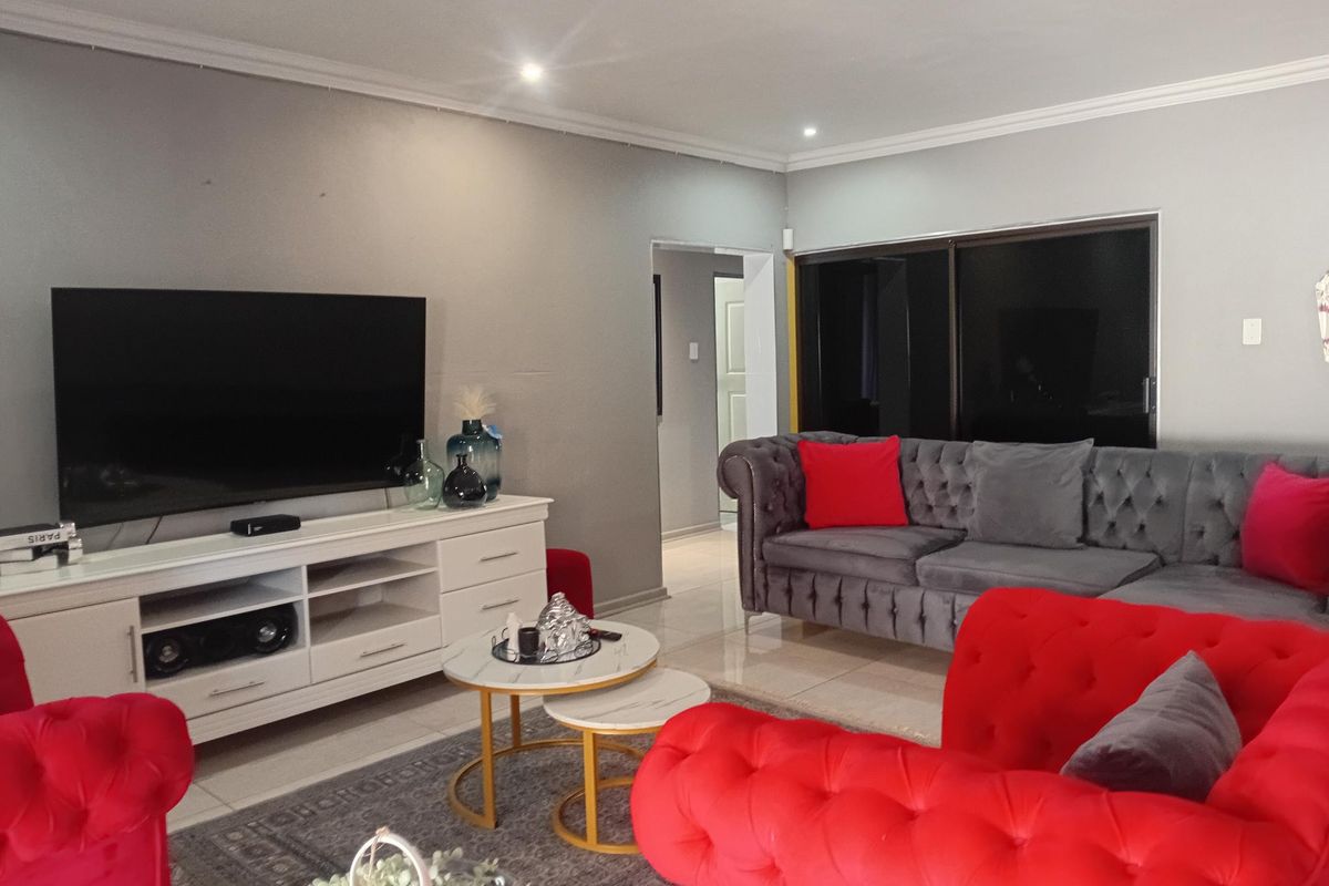 A well-maintained living room featuring tiled flooring, recessed downlighting, and a sliding glass door providing access to the exterior.