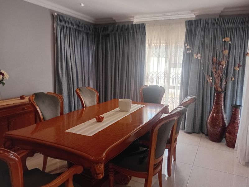 A formal dining room featuring tiled flooring, decorative ceiling cornices, and recessed lighting, providing a classic space for family meals and entertaining.