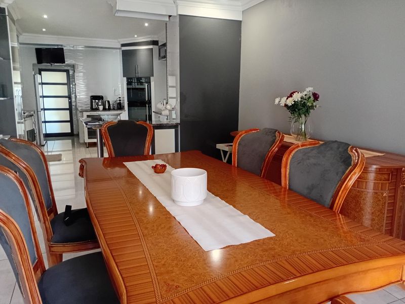 Open plan dining area flowing into a modern kitchen with tiled floors, recessed lighting, and contemporary cabinetry.