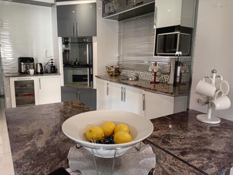 Modern kitchen featuring granite countertops, built-in oven and microwave, sleek cabinetry, and a mosaic tile backsplash.