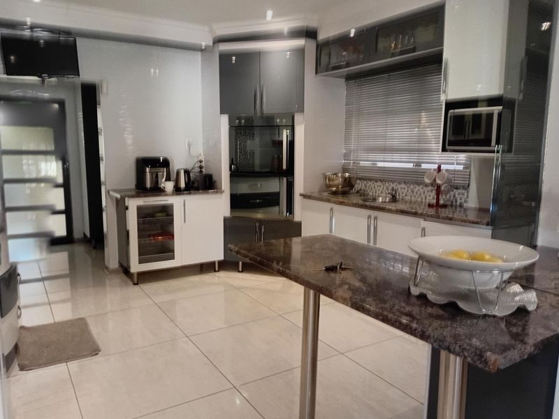 Modern kitchen featuring granite countertops, a central island, built-in oven and microwave, and ample cabinetry with a stylish mosaic tile backsplash.
