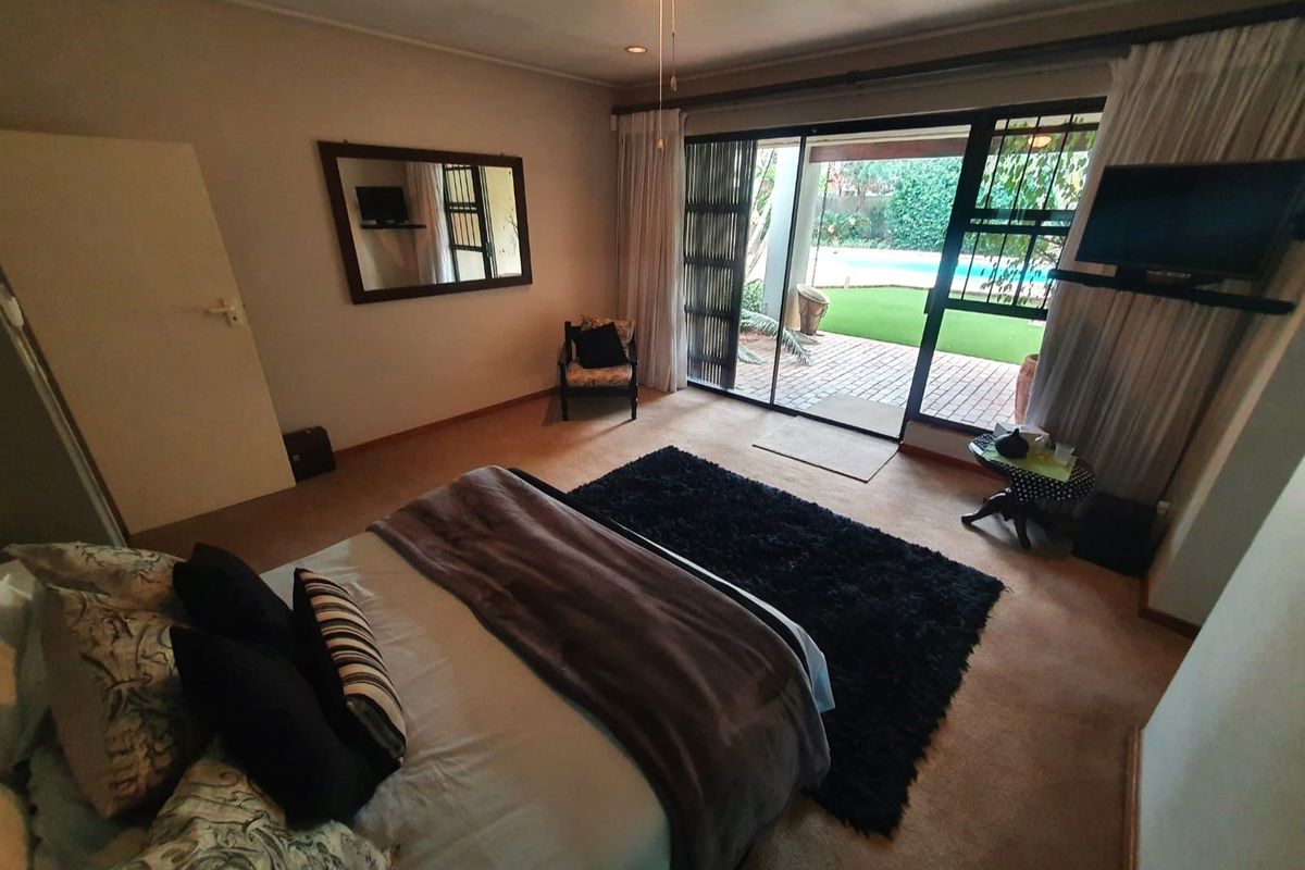 Spacious bedroom featuring large sliding glass doors that open directly onto a private patio and garden area, providing ample natural light.
