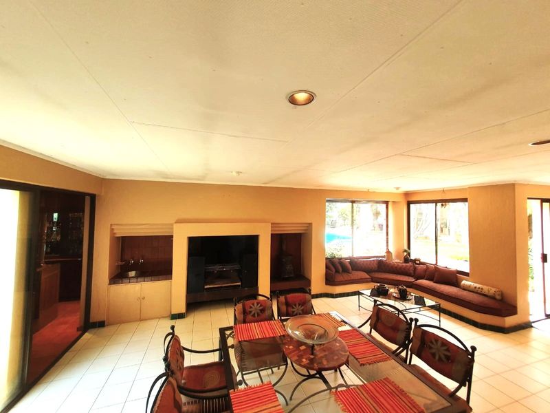 Spacious open-plan living and dining area featuring a built-in fireplace, integrated bar area, and large windows overlooking the garden.