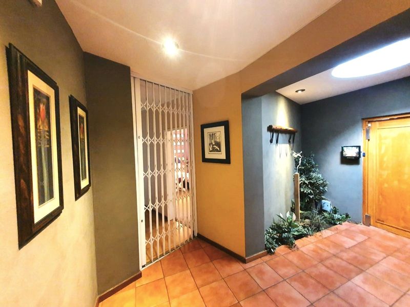 An interior entrance hall featuring terracotta floor tiles, a security gate, and a built-in indoor planter area with recessed lighting.