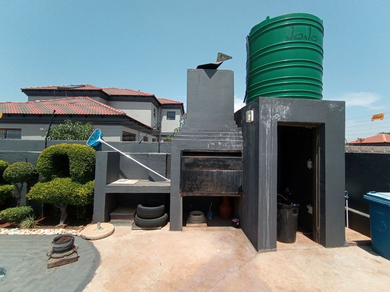 Outdoor entertainment area featuring a built-in braai, masonry structure, and an integrated water storage tank.
