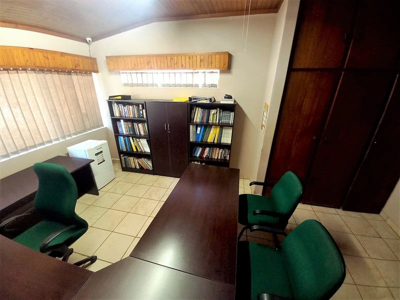A functional office space featuring tiled flooring, built-in wooden cabinetry, and a timber-paneled ceiling, suitable for a home workspace or study.