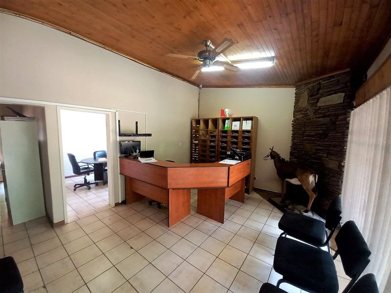 Office reception area featuring a built-in wooden counter, stone-clad feature wall, tiled flooring, and a timber-paneled ceiling with a central fan.