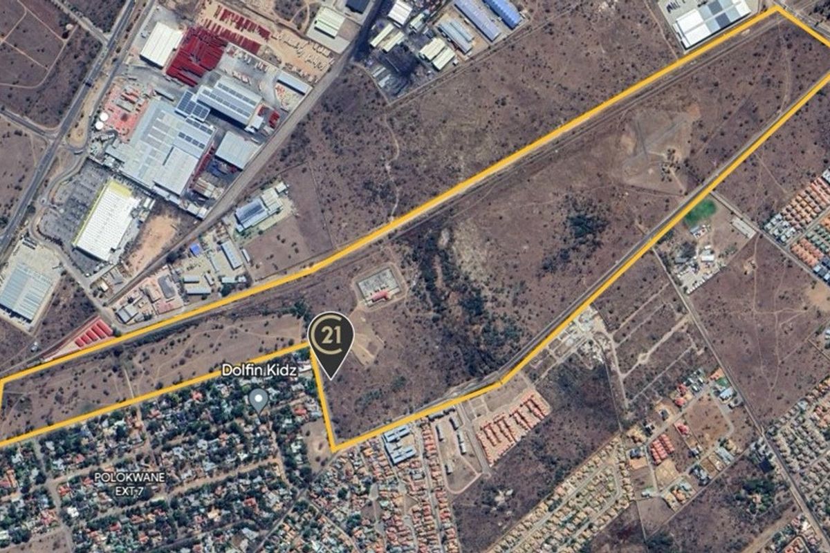 Aerial view of a large, undeveloped residential land parcel with clear boundary demarcations, situated in a developing urban area.