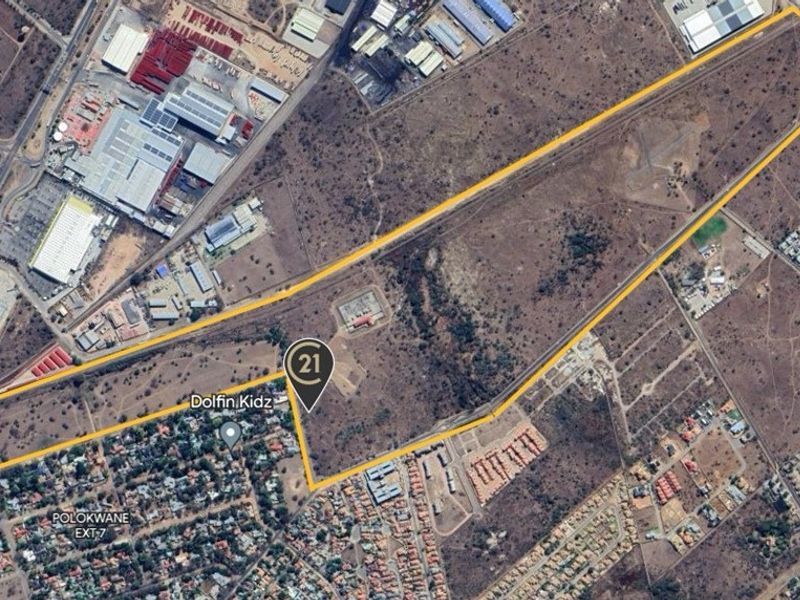 Aerial view of a large, undeveloped residential land parcel with clear boundary demarcations, situated in a developing urban area.
