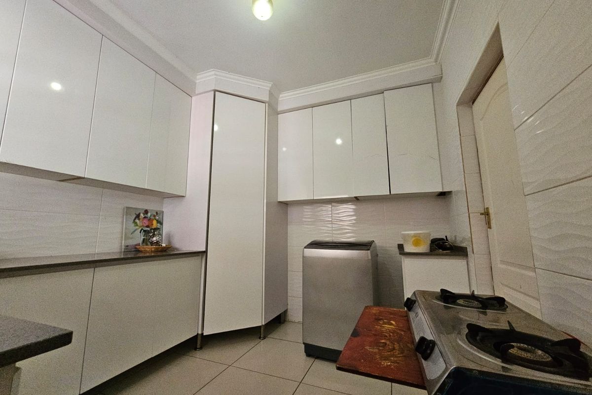 A functional kitchen featuring white cabinetry, tiled walls, and tiled flooring, providing ample storage and workspace for daily culinary activities.