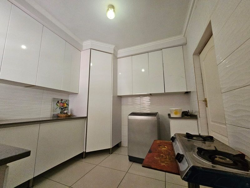A functional kitchen featuring white cabinetry, tiled walls, and tiled flooring, providing ample storage and workspace for daily culinary activities.