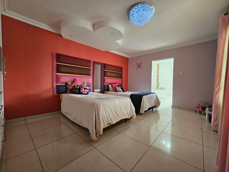 Spacious bedroom featuring large format floor tiles, a decorative recessed ceiling feature, and an en-suite bathroom access.