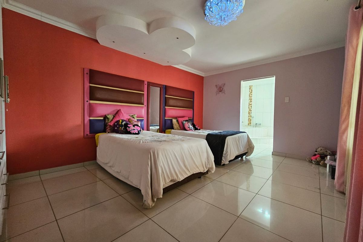 Spacious bedroom featuring large format floor tiles, a decorative recessed ceiling feature, and an en-suite bathroom access.