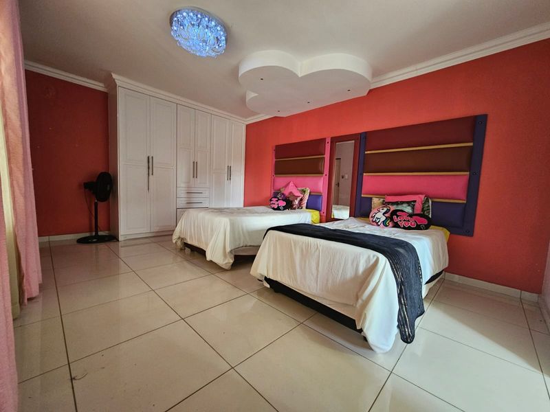Spacious bedroom featuring built-in white cabinetry, tiled flooring, a decorative ceiling feature, and integrated headboard panels.
