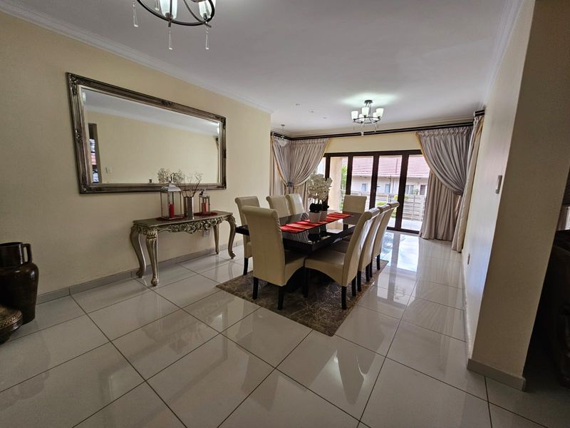 Spacious dining room featuring polished porcelain floor tiles, decorative crown molding, and large sliding glass doors providing access to the outdoor patio area.
